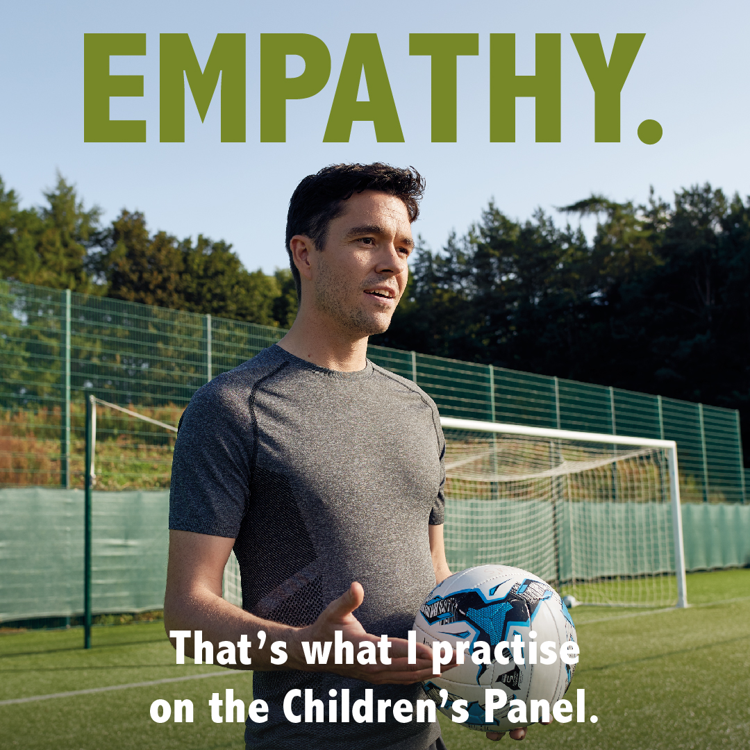 A football coach talking and holding a ball on a field, with the word Empathy above them.